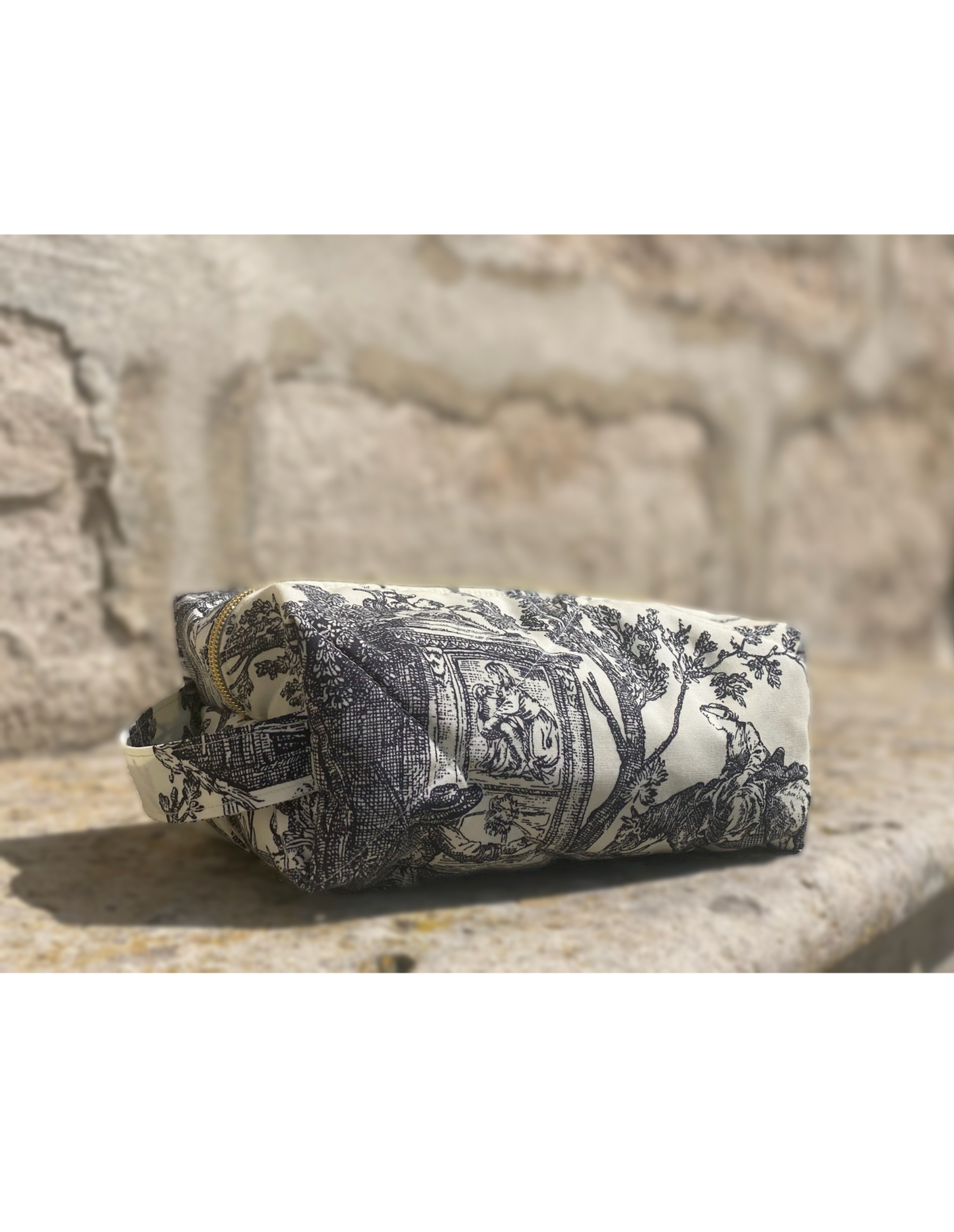 Trousse de toilette posée devant un château français – accessoire fait main
