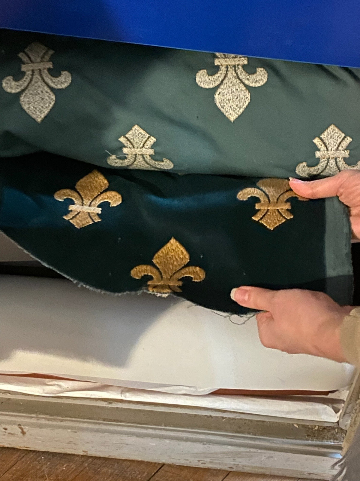 Green velvet embroidered with gold fleurs-de-lis, unfolded in a château storeroom